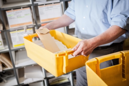 Gelbe Postkiste mit Tagespost und Briefen, die digitalisiert werden